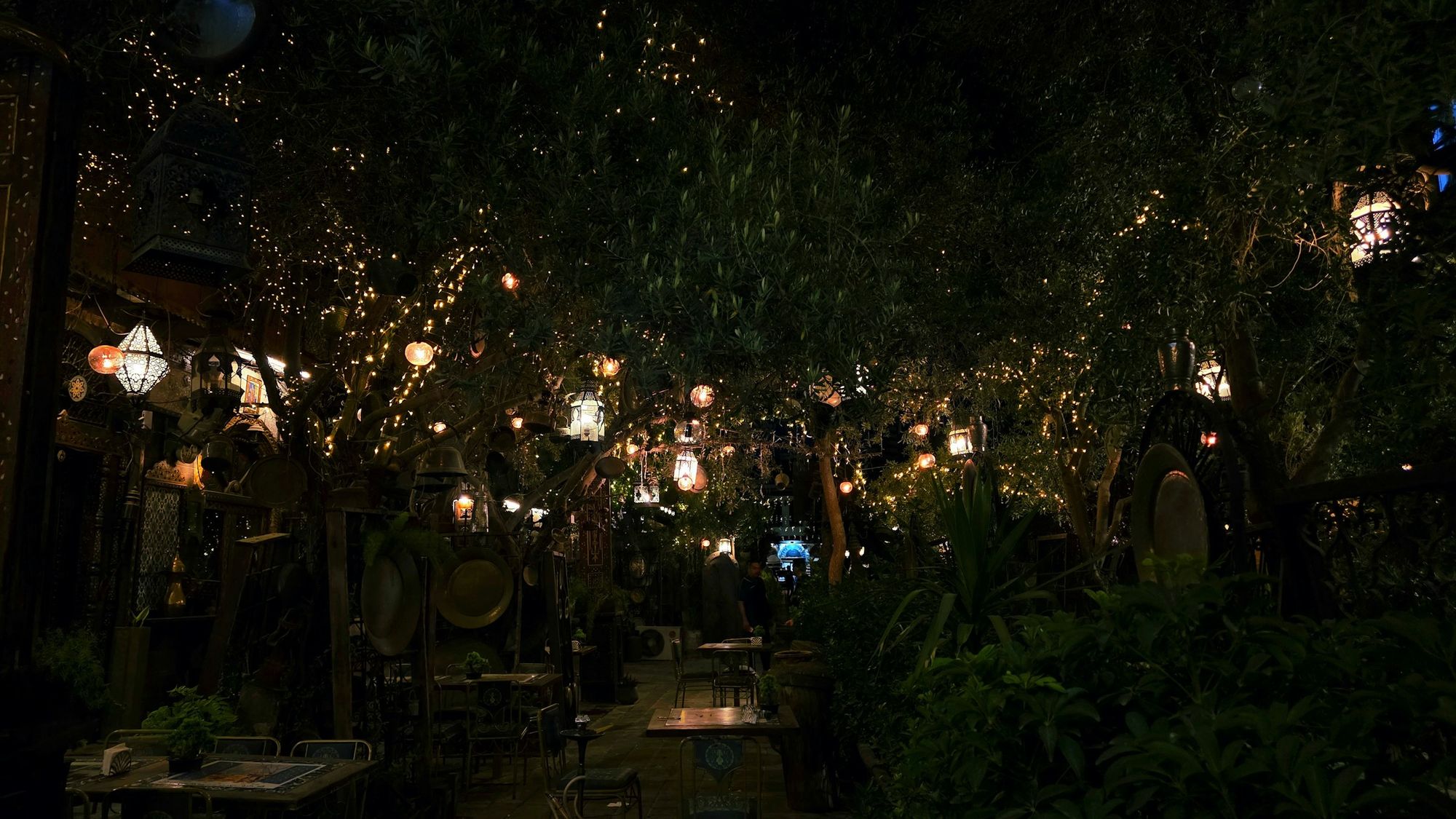 Garten mit hängenden Lichtern und Laternen am Abend