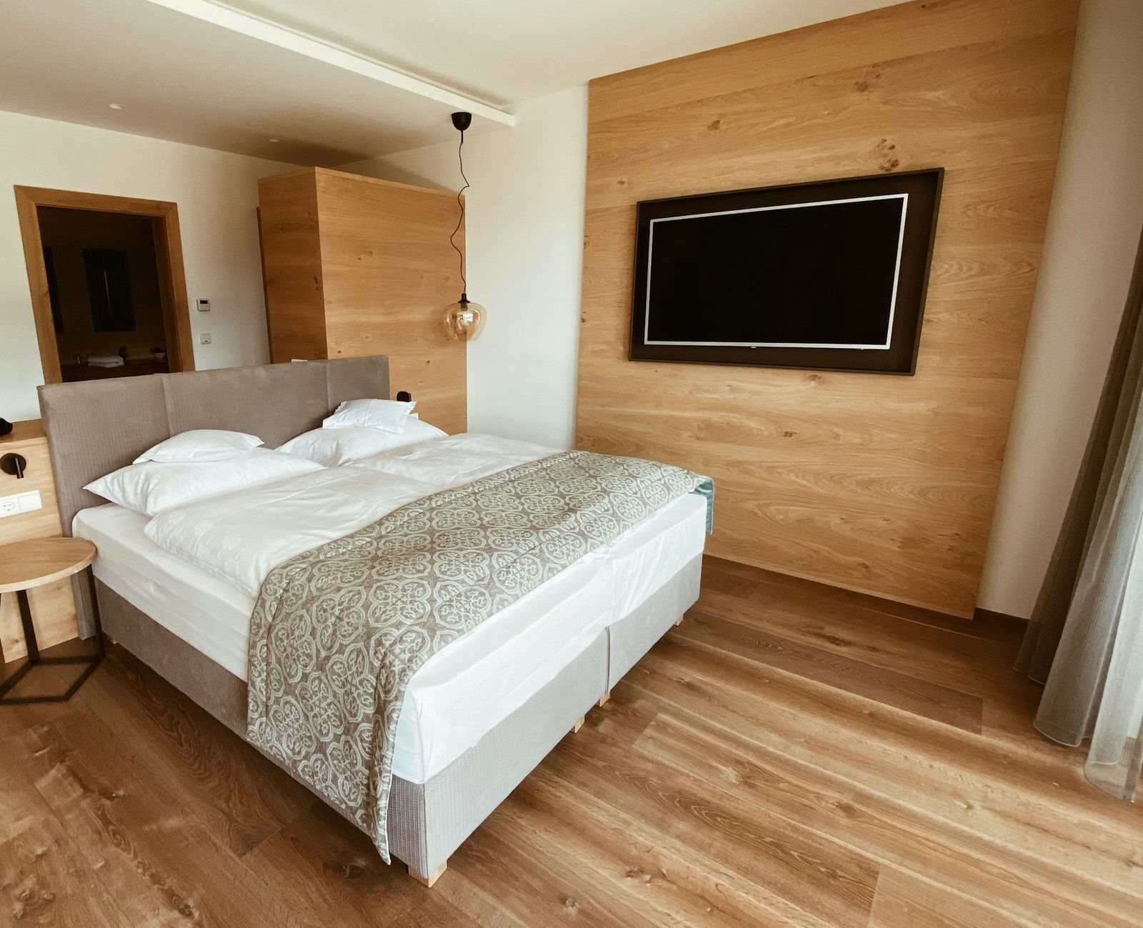 Zimmer mit weißem Bett und Holzwand